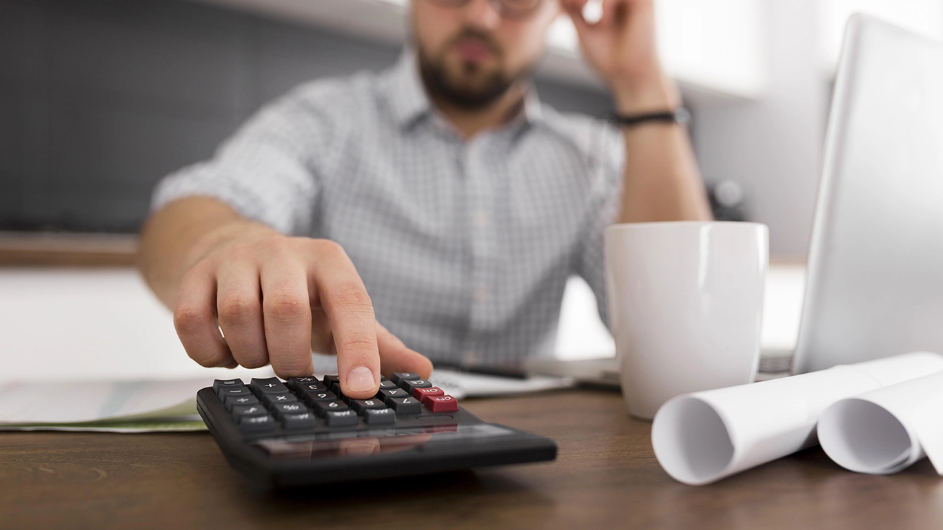 Close-up image of man using a calculator at his desk